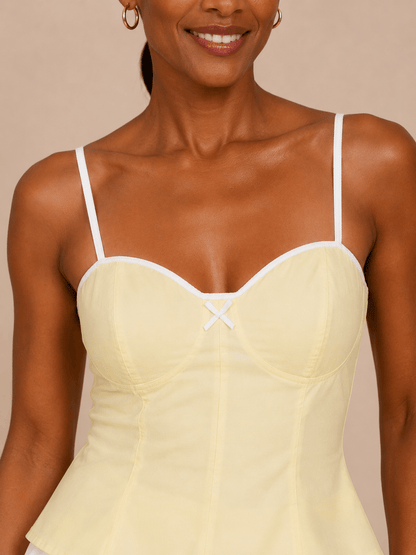 Detalle del escote corazón y lazo frontal del Top Cashia Bari amarillo sobre fondo nude.
