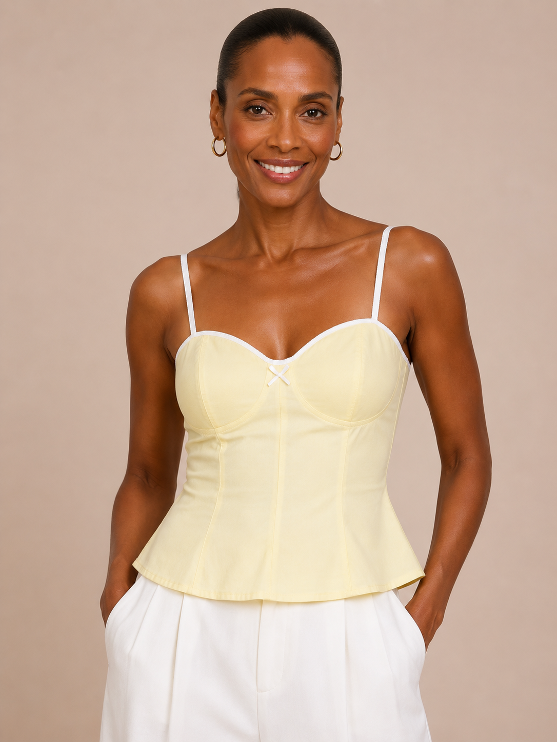 Medio plano frontal superior del Top Cashia Bari amarillo con tirantes blancos y escote corazón sobre fondo nude.