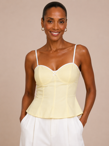 Medio plano frontal superior del Top Cashia Bari amarillo con tirantes blancos y escote corazón sobre fondo nude.