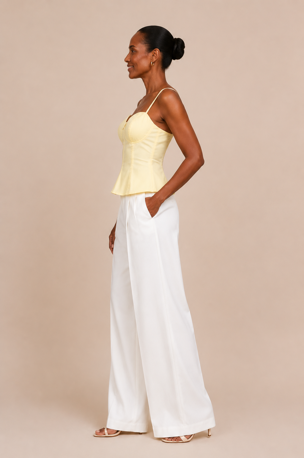 Modelo Cashia de perfil con Top Cashia Bari amarillo y pantalón blanco wide leg sobre fondo nude.