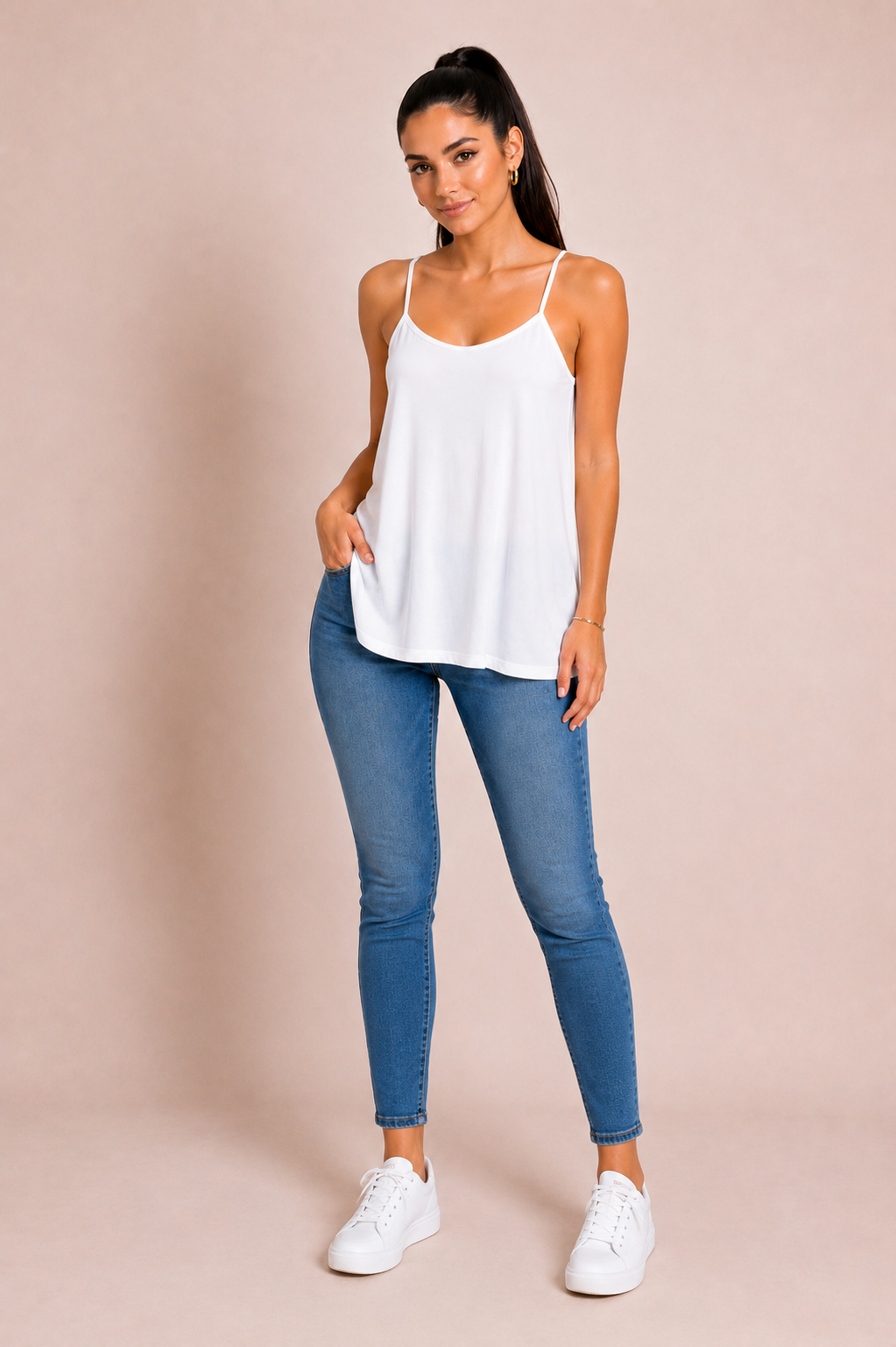 Modelo con Top Cashia Basic Cruzado blanco, tirantes finos planos y corte holgado, combinado con vaqueros y zapatillas blancas.
