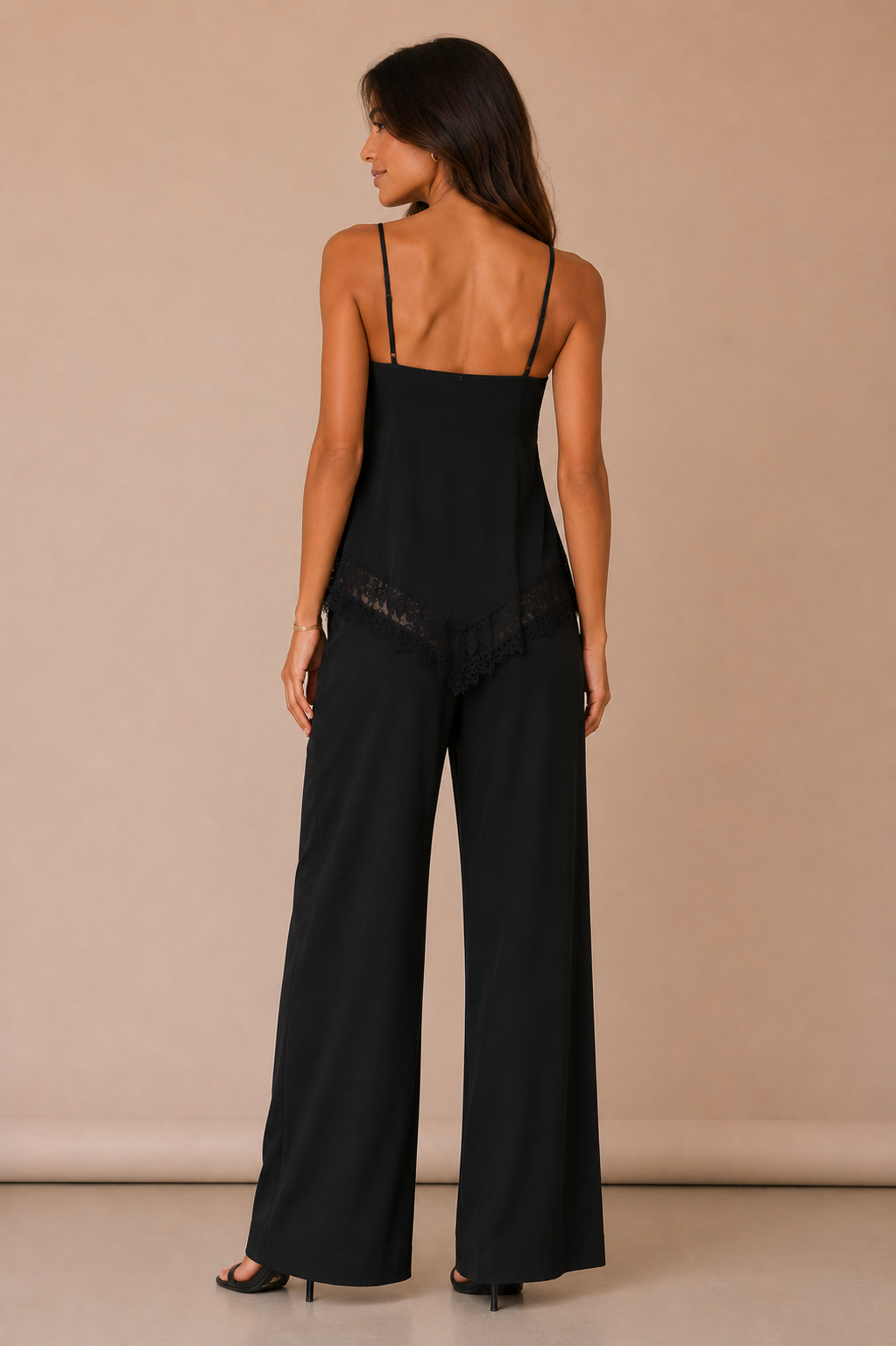 Modelo Cashia de espaldas con Top Cashia Lucca negro, diseño recto por detrás, tirantes finos y pantalón negro sobre fondo nude.
