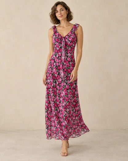 Modelo Cashia talla M con vestido largo negro de flores fucsias, tirantes con volantes y falda de caída natural.