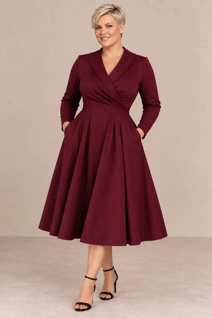 Modelo rubia de pelo corto talla 2XL luciendo vestido Cashia París burdeos con manga larga y falda midi.
