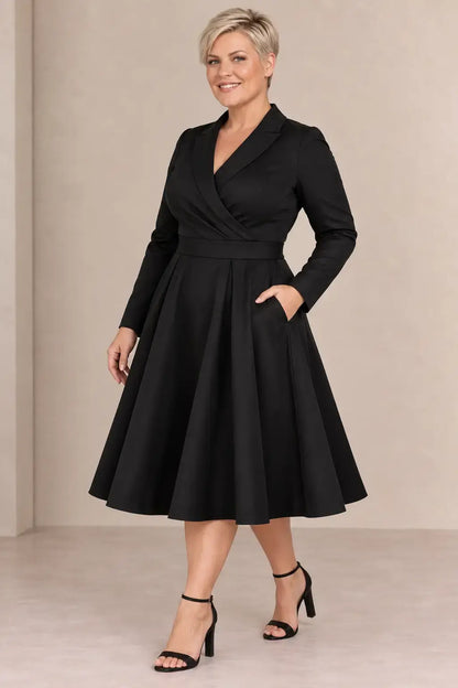 Vestido Cashia París negro en modelo rubia de pelo corto talla 2XL, escote cruzado, cintura marcada y falda midi.