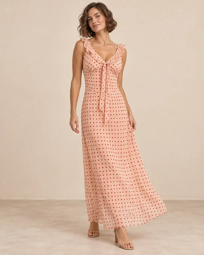 Modelo Cashia talla M con vestido largo rosa de lunares rojos, escote en V con lazada y caída recta y fluida.