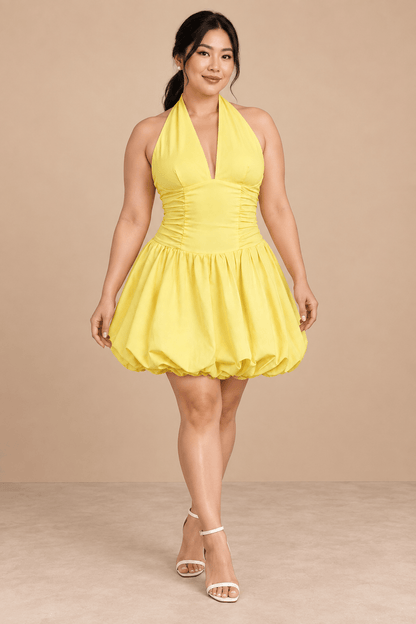Modelo Cashia talla L con Vestido Cashia Sorrento amarillo, escote halter y falda globo, en pose dinámica sobre fondo nude