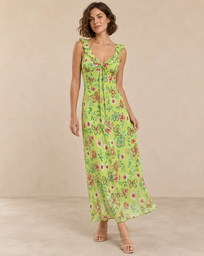 Modelo Cashia talla M con vestido largo verde lima de estampado floral y mariposas, escote en V y caída fluida.